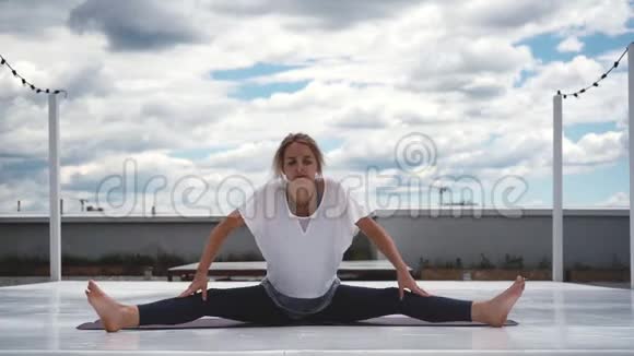 年轻女子正在练习瑜伽坐在广角前弯姿势中视频的预览图