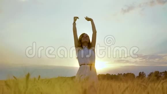 日落时分快乐的女孩在麦田里举手视频的预览图