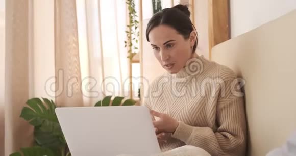 年轻女子在家睡觉时使用笔记本电脑进行视频通话视频的预览图