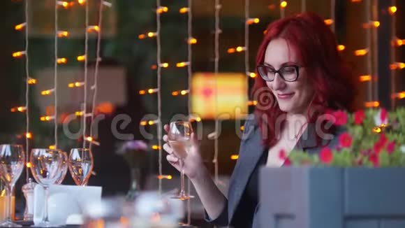 一位留着红头发的商人坐在餐馆的餐桌旁手里拿着一杯香槟视频的预览图