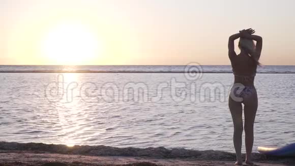 穿比基尼的金发少女正在看海滩上的日落视频的预览图