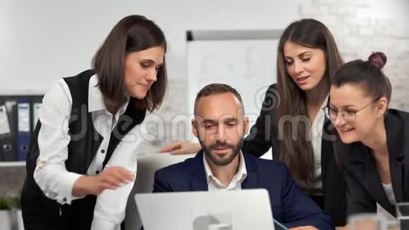 一群年轻的微笑商人西装革履地与男性老板讨论使用笔记本电脑的项目视频的预览图