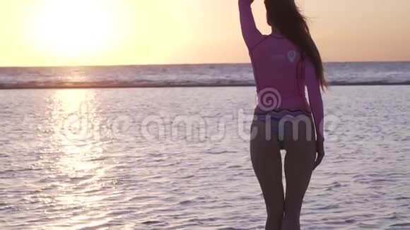 穿比基尼和粉色上衣的苗条女人正在看海滩上的日落视频的预览图