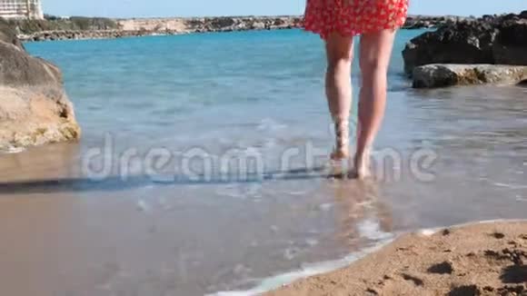年轻的白种人女孩来到海边穿着红色短裙在海滨散步的布鲁内特女孩有魅力的女人走路视频的预览图