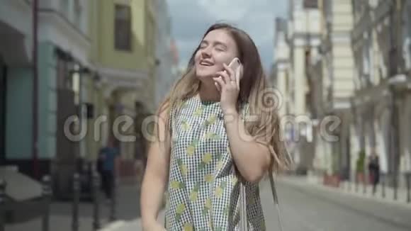 可爱的年轻女人用手机在城市大街上聊天穿着时髦夏装的有趣女孩视频的预览图