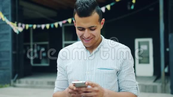 有魅力的阿拉伯男人在户外使用智能手机触摸屏幕的肖像视频的预览图