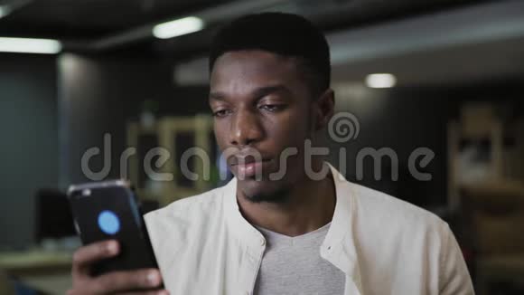 非洲年轻人拿着智能手机发短信在现代办公室喝咖啡或茶视频的预览图