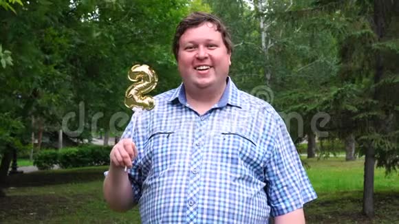 大个子拿着金色气球在户外做2号2周年庆祝晚会视频的预览图