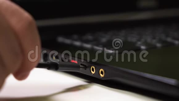 关闭男性手连接灰色和黑色c型电缆到笔记本电脑与发光红色USB端口视频的预览图
