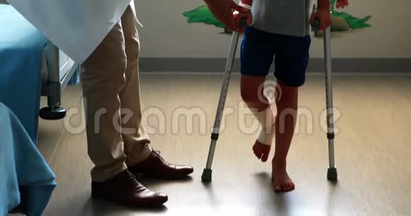 男医生协助受伤男孩拐杖行走视频的预览图