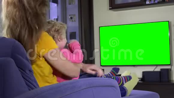 快乐的母亲和她可爱的女儿在沙发上看电视滑稽卡通片视频的预览图