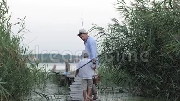 亲情父子亲情父母带着可爱的小男孩在夏天全家闲暇时到河边的码头钓鱼视频的预览图