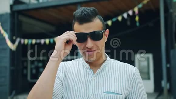 动作缓慢年轻英俊的阿拉伯人摘下太阳眼镜在户外微笑视频的预览图