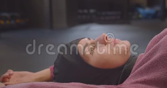 年轻坚定的穆斯林女性戴着头巾疲惫地躺在健身房的特写镜头视频的预览图