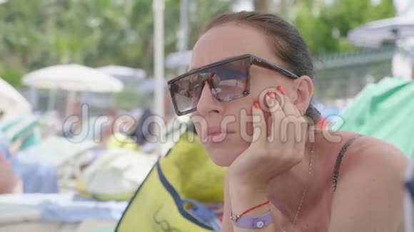 年轻漂亮的女孩戴着太阳镜海滩倒影海上度假的概念视频的预览图