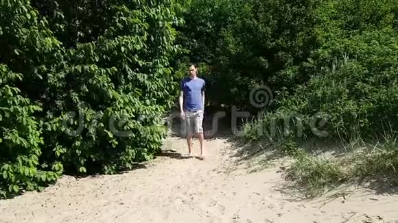 一个穿短裤和t恤的年轻人在沙滩上他一瘸一拐的有一个残疾脑瘫视频的预览图