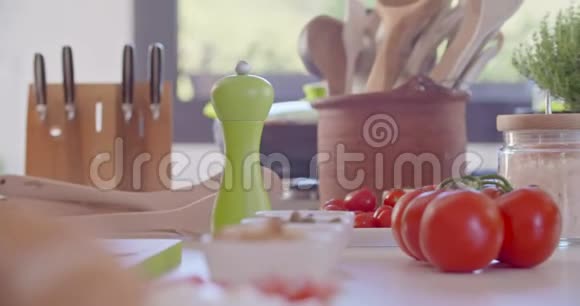 厨房桌子的细节西红柿和工具厨房桌子上的勺子刀子和食物健康饮食蔬菜沙拉视频的预览图