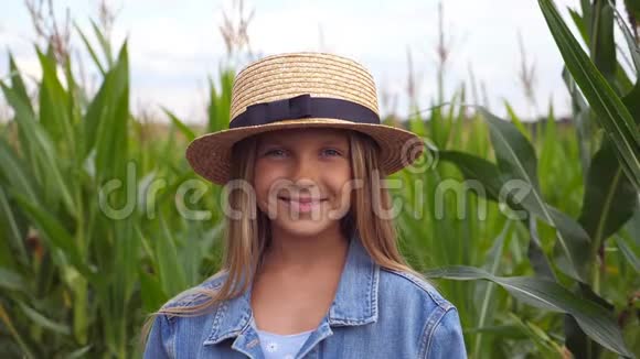 美丽的小女孩戴着草帽看着镜头在草地上笑幸福的小孩和视频的预览图
