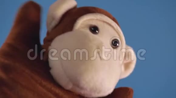 手边蓝色背景的软木偶玩具木偶戏的概念与傀儡猴子的手特写镜头视频的预览图