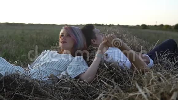 爱的男人和女人手牵着手躺在干草堆上视频的预览图