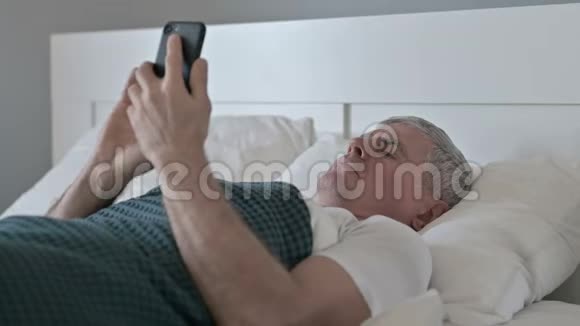 睡在床上时使用智能手机的中年人视频的预览图