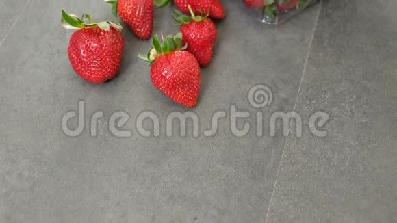 1公斤新鲜草莓装在灰色木制背景的塑料盒子里视频的预览图