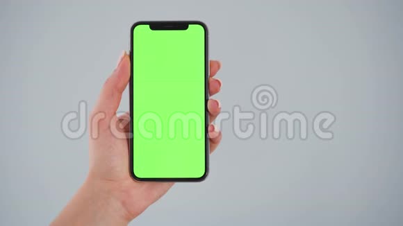 女性手拿着智能手机灰色背景上有绿色屏幕铬钥匙复制空间视频的预览图