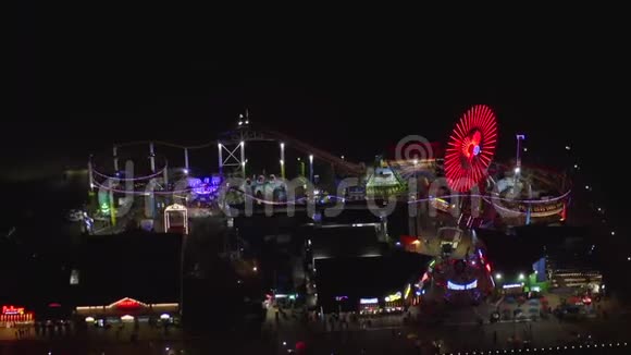 在圣塔莫尼卡码头上欣赏夜晚摩天轮和五颜六色的灯光视频的预览图