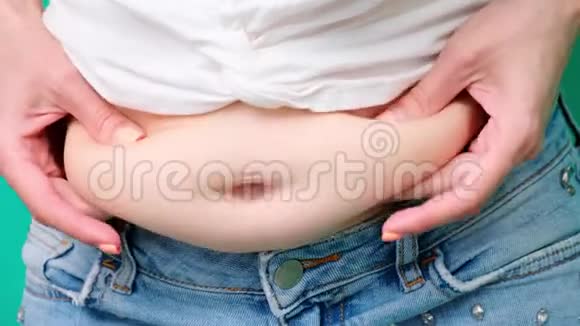 一名妇女的特写镜头她触摸并测量她的腹部脂肪视频的预览图