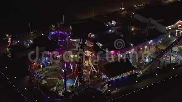 在圣塔莫尼卡码头上欣赏夜晚摩天轮和五颜六色的灯光视频的预览图