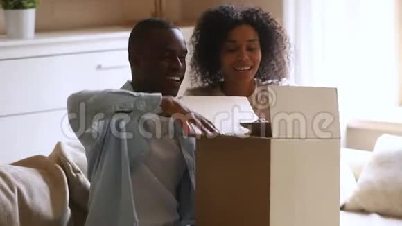快乐的非洲夫妇的顾客打开纸板箱满意地购买视频的预览图