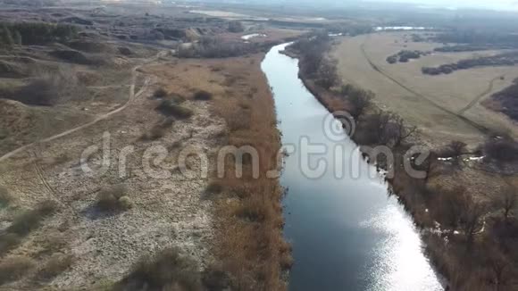 乡间宁静的河流从上面看这是一条神奇的河流平静的河水坐落在大自然的一片春天的森林旁视频的预览图
