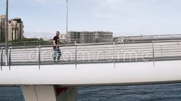 一个人走过河上的一座桥从他的一侧看到了一个无人机视频的预览图