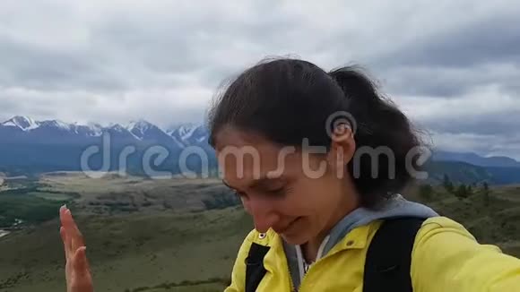 布鲁内特女孩在去自拍微笑和海浪向相机问好去山里旅行视频的预览图