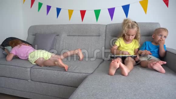 金发姐姐和弟弟用平板电脑和红头发女孩在沙发上哭泣视频的预览图