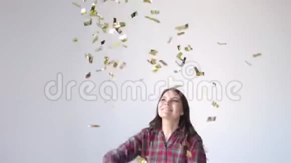 美丽的快乐女孩跳舞和投掷金色纸屑慢动作视频的预览图