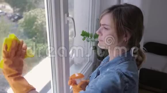 戴手套的生病女孩用清洁喷雾清洗窗户并因呼吸道疾病过敏观念打喷嚏视频的预览图