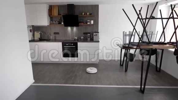 机器人吸尘器在公寓里工作移动到厨房地板上自动清洁家庭视频的预览图