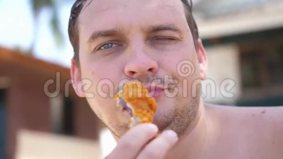 肥醉的大胡子男人在户外吃鸡翅快餐慢动作视频的预览图