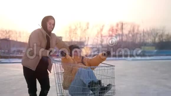 快乐的年轻夫妇骑着手推车在商场停车场阳光照在背景上慢动作视频的预览图