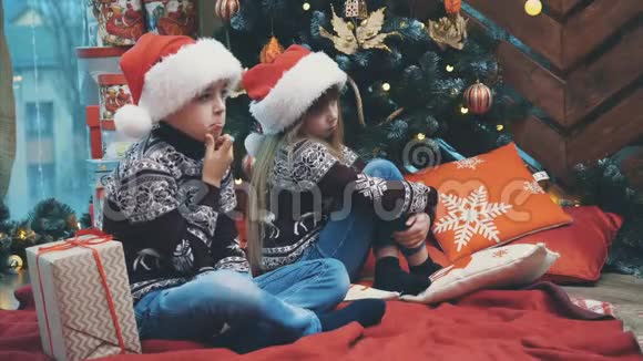 可爱的4k视频哥哥在圣诞节的时候坐在树旁给妹妹送圣诞礼物盒视频的预览图