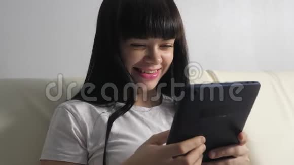 女孩用笔记本电脑数字平板电脑制作网上销售购物概念一个躺在沙发上看商店的女人视频的预览图