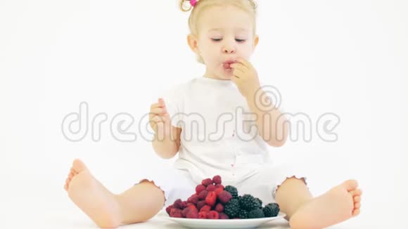 可爱的金发女孩在白色背景下吃浆果视频的预览图