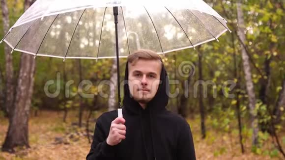 一个年轻人在雨天沿着秋天公园散步的肖像视频的预览图