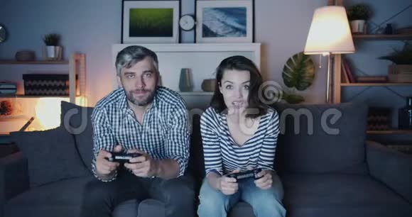 幸福的一对夫妻深夜在家玩电子游戏面带微笑视频的预览图