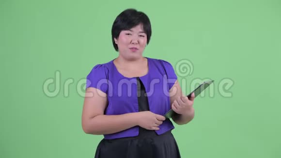 快乐年轻体重超重的亚洲女人拿着剪贴板说话视频的预览图