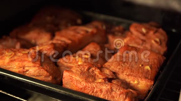 把烤好的排骨放在烤箱里的托盘上加蒜的调味肉在烤箱里炒视频的预览图