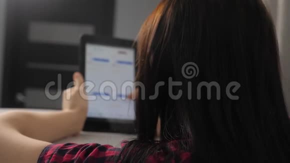 网上购物的概念坐在网上商店看商品的年轻女孩在数字平板电脑上购物妇女视频的预览图