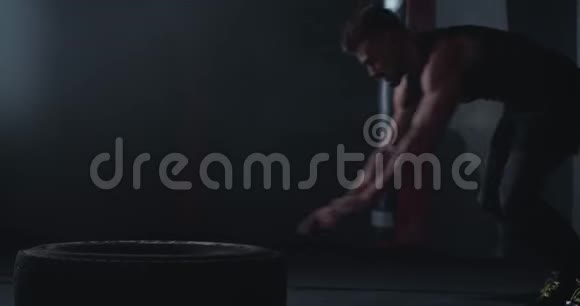 健身肌肉男做交叉健身运动在体育课上在一个大橡胶轮胎上做俯卧撑他出汗了视频的预览图
