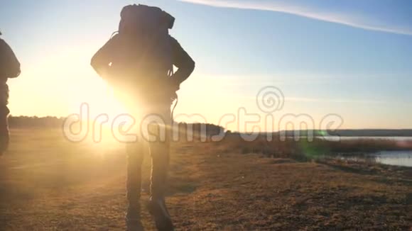 两名游客一起背着背包慢动作走着在阳光下剪影在日落时晒太阳视频的预览图